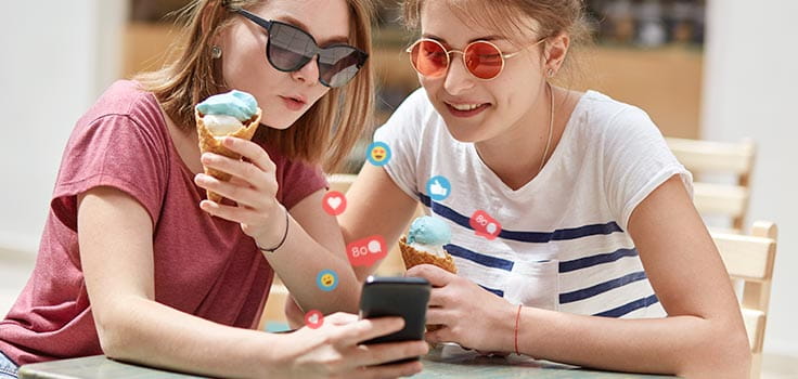 mujeres jovenes con helado en la mano y viendo un celular