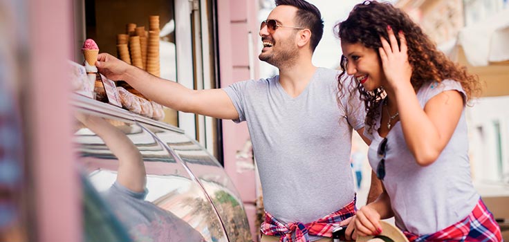 pareja comprando helados parados al frente de nevera refrigerada