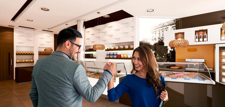 pareja estrechando las manos en el interior de heladería frente a vitrinas refrigeradas 