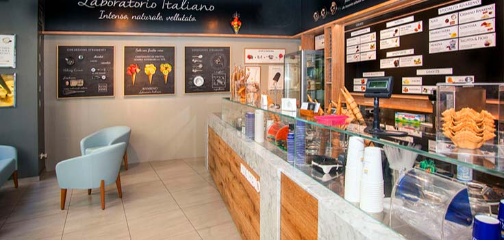 interior de heladeria con vitrina con vasos y conos de helado