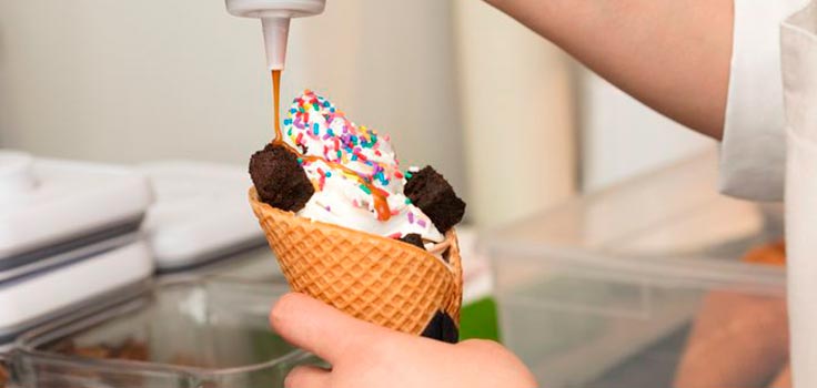 persona sirviendo helado de vainilla con chispas de colores